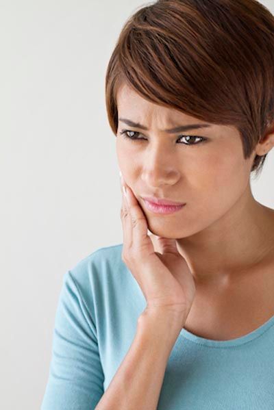 woman holding her mouth from tooth pain in need of an emergency dentist