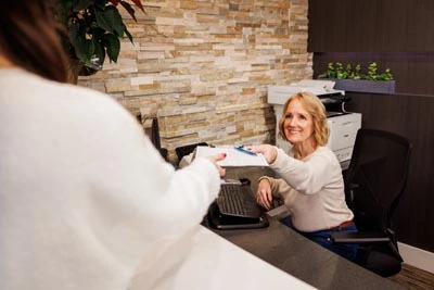 front office coordinator helping patient fill out insurance paperwork